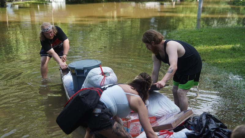 Scott Conrad, left, Joseph Workman, right, and Kesley Patterson, back to camera, push a kayak...